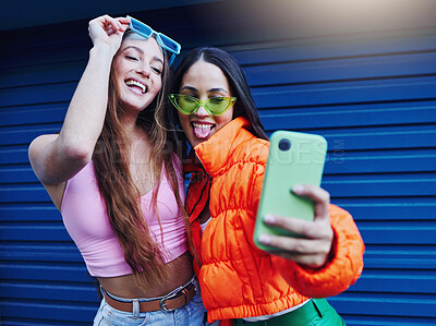 Buy stock photo Fashion, selfie and friends with phone on blue background with style, cool sunglasses and urban clothes. Social media, smartphone and women smile for photo on weekend, vacation and holiday in city