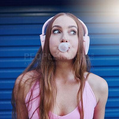 Buy stock photo Young girl, bubblegum and headphones, face isolated on blue background, listen to music with freedom and fashion. Blowing bubble, candy and crazy gen z youth in studio, fun with radio or audio tech