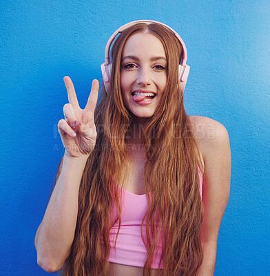 Buy stock photo Music, peace and tongue with the portrait of a woman on a blue background while listening to the radio. Face, hand and headphones with an attractive young female streaming an audio playlist or song