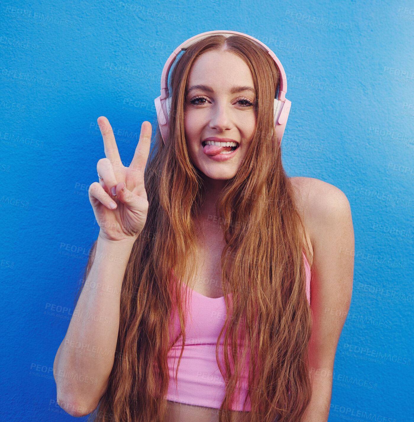 Buy stock photo Music, peace and tongue with the portrait of a woman on a blue background while listening to the radio. Face, hand and headphones with an attractive young female streaming an audio playlist or song