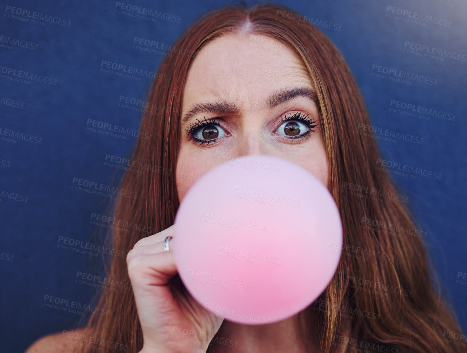 Buy stock photo Closeup portrait, girl and bubblegum by wall, outdoor and urban adventure for funny, comic face and happy. Gen z woman, city and blue background with pink chewing gum, bubble and blowing for fun game