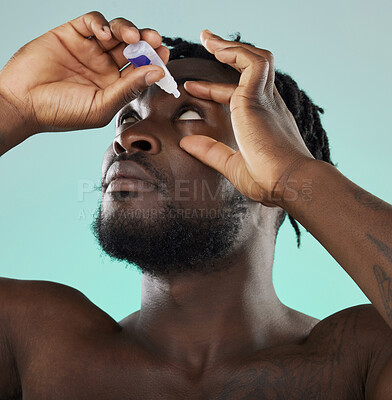 Buy stock photo Black man, studio and eye drop for health vision, wellness and self care by blue backdrop for morning routine. African gen z model, eyes and product for healthcare, medicine and medical serum bottle