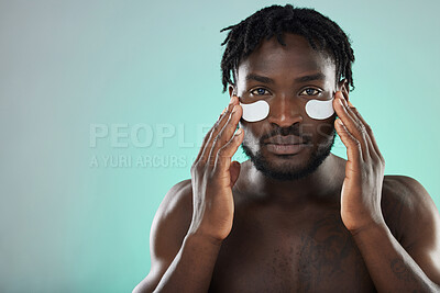 Buy stock photo Skincare, eye pads and portrait of a black man in studio for healthy, cosmetic and natural face routine. Health, wellness and African guy with a facial treatment by blue background with mockup space.