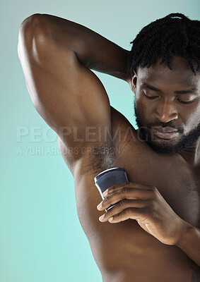 Buy stock photo Grooming, hygiene and black man with armpit deodorant isolated on a blue background in studio. Skincare, cleaning and African model with a product for body odor and morning routine on a backdrop