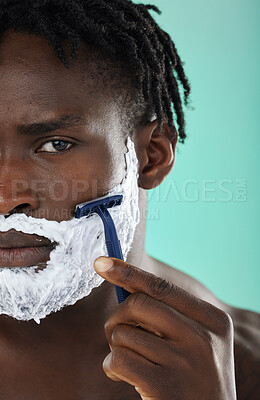 Buy stock photo Black man, shaving and studio with skincare foam, razor and facial cosmetics for beauty by blue background. African gen z model, hair removal cream and shave for aesthetic, cleaning and face grooming