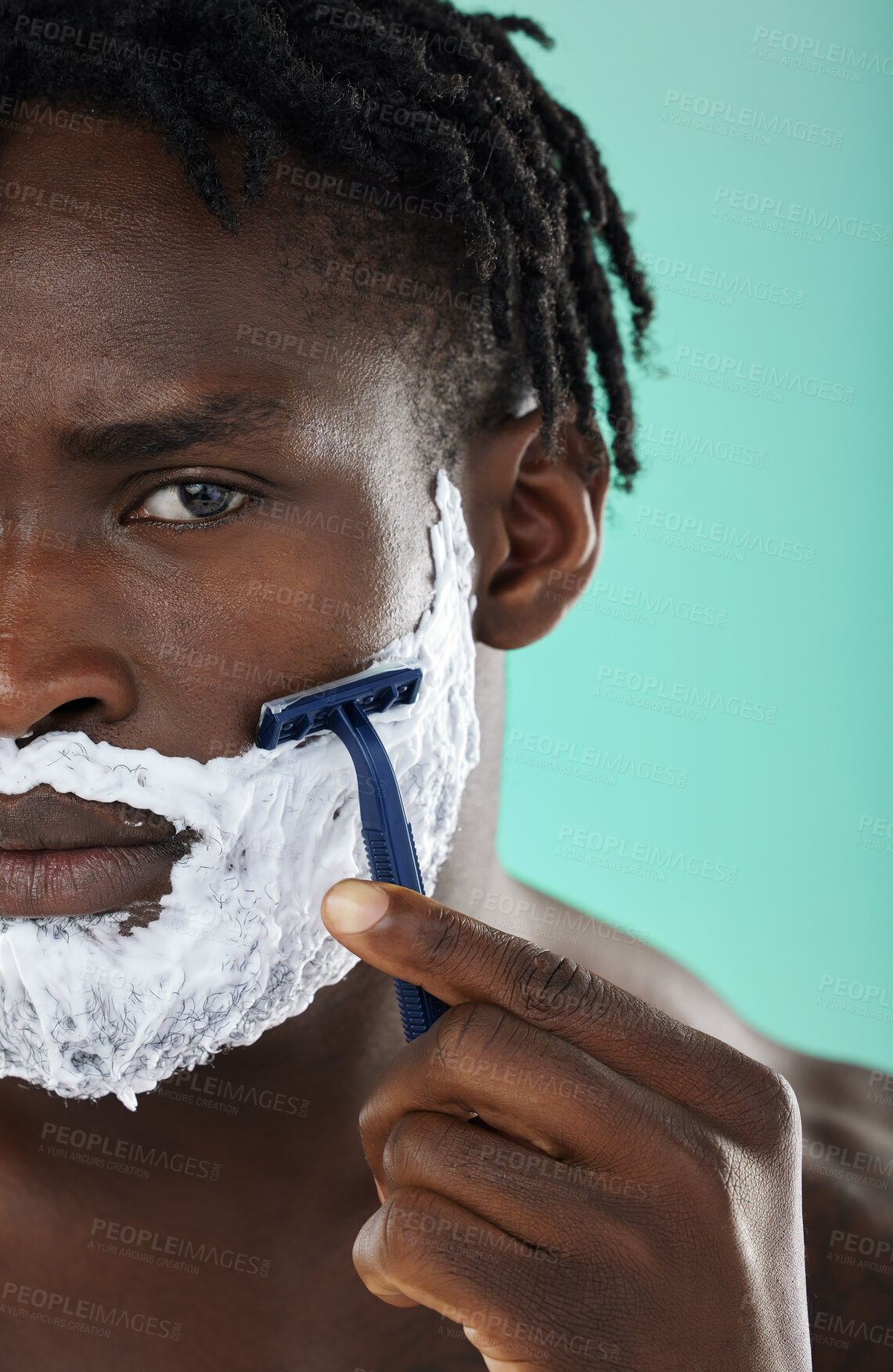 Buy stock photo Black man, shaving and studio with skincare foam, razor and facial cosmetics for beauty by blue background. African gen z model, hair removal cream and shave for aesthetic, cleaning and face grooming