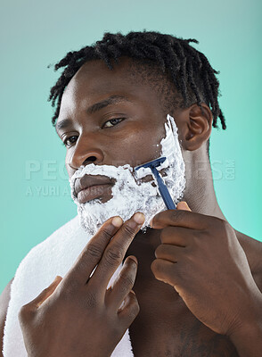 Buy stock photo Shaving face with skincare cream, black man with razor on studio background and on smooth facial hair growth. Confident young model grooming, body hygiene and cleaning beard with cosmetic product