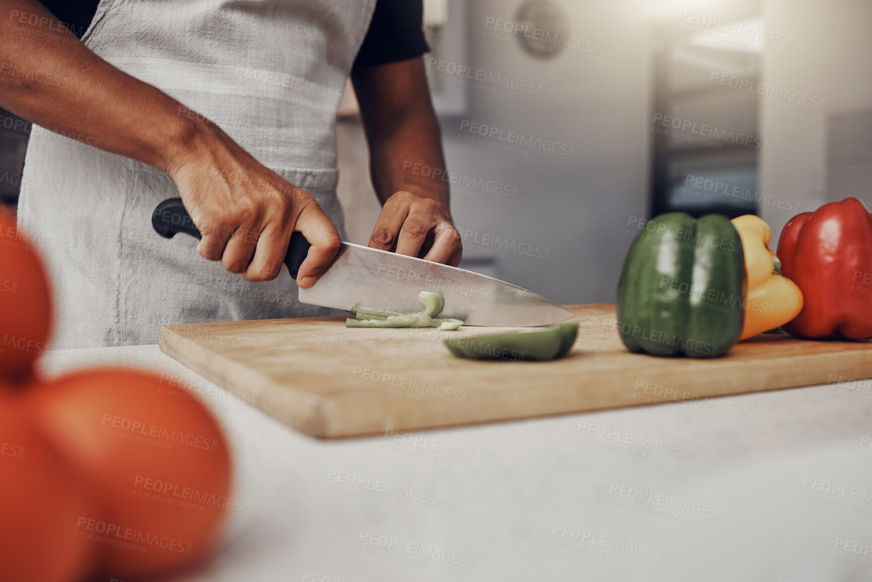 Buy stock photo Hands, food and cooking with a man in the kitchen, cutting a green pepper on a wooden chopping board. Salad, health and diet with a male chef preparing a meal while standing alone in his home