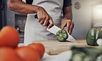 Hands, food and cooking with a man cutting a green pepper in the kitchen on a wooden chopping board. Salad, health and diet with a male chef preparing a meal while standing alone in his home