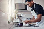 Cleaning kitchen, washing dishes and a man in house, home or apartment to clean for safety from bacteria. Male cleaner person at sink with a cloth in hands for hygiene and a healthy lifestyle