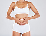 Health, wellness and hands on stomach of woman in studio for nutrition, healthy eating and digestion. Fitness, body care and abdomen of female model for diet, lose weight and liposuction treatment