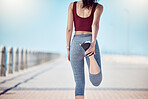 Fitness, woman and stretching legs at beach promenade for exercise, wellness and training. Back of athlete, runner and person warm up body at seaside for summer workout, sports and marathon running 