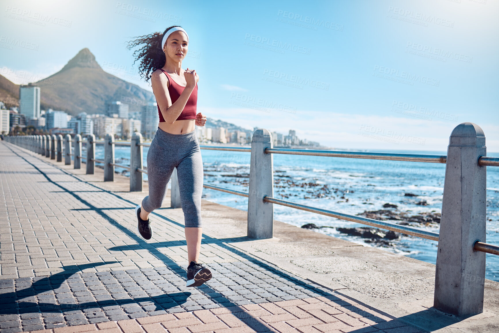 Buy stock photo Woman running at ocean promenade for fitness, energy and strong body in Cape Town. Female runner, sports person and athlete at seaside for marathon, cardio exercise and healthy summer workout in sun