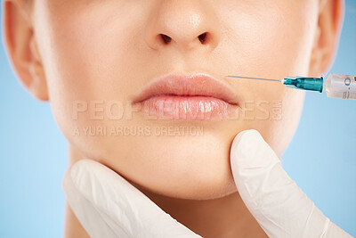Botox, facial and lip filler by woman with cosmetic injection isolated against a studio blue background. Beauty, beauty and closeup of girl get plastic surgery at a cosmetology clinic using a syringe