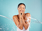 Water splash, skincare and woman in a studio with a beauty, cosmetic and natural face routine. Health, wellness and female model with a fresh organic facial treatment isolated by a blue background.