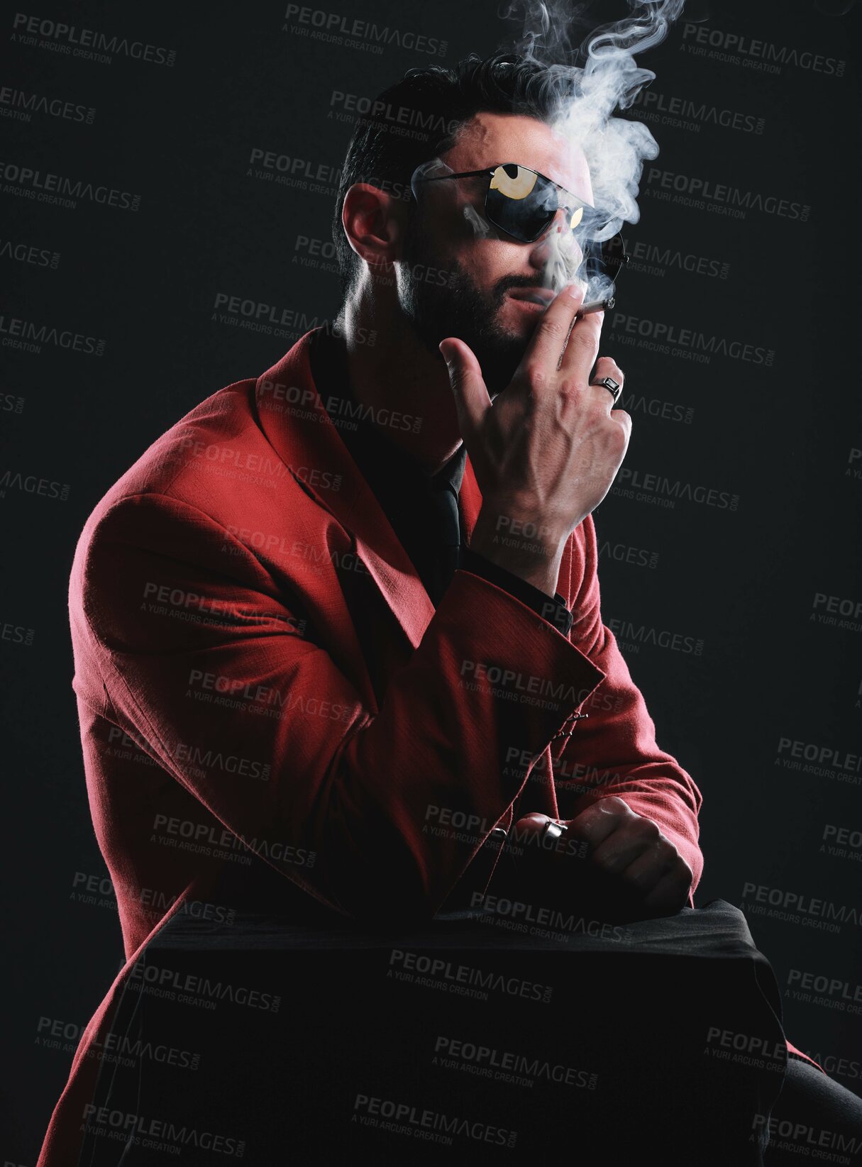 Buy stock photo Fashion, smoking and red with a man model in studio on a dark background wearing a suit for style. Smoke, mafia and edgy with a handsome young male posing on black space holding a cigarette