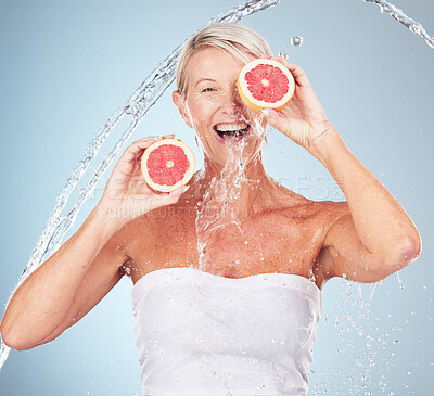 Buy stock photo Woman, studio portrait and grapefruit with water splash, smile and happy for wellness by blue background. Senior model, organic citrus fruit and vitamin c for health, nutrition and self care process