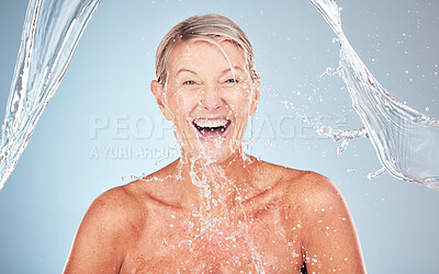 Buy stock photo Skincare, senior and portrait of a woman with a water splash isolated on a blue background. Self care, happy and face of an excited elderly model cleaning her body for wellness on a studio backdrop