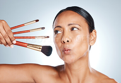 Buy stock photo Face, beauty and senior woman with makeup brushes in studio isolated on a gray background. Cosmetics, skincare products and mature female model pout lips with tools to apply foundation and powder.