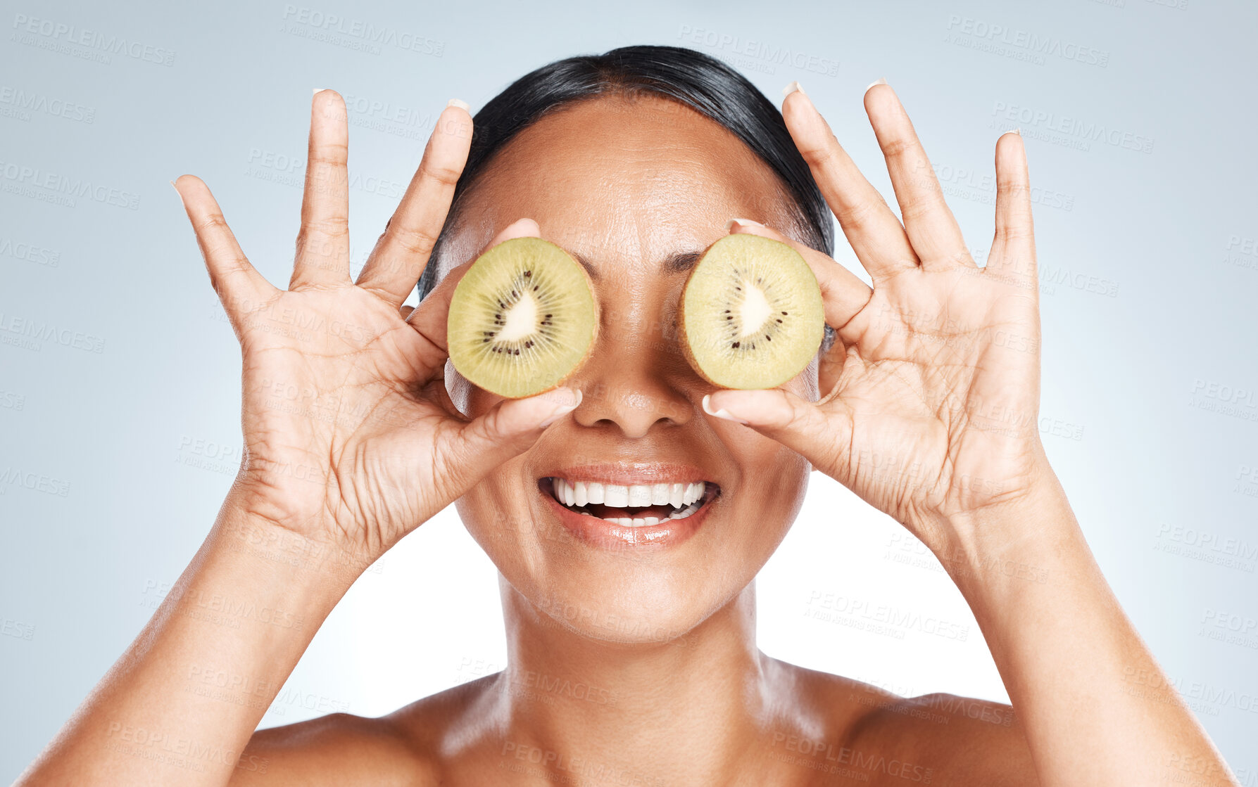 Buy stock photo Skincare, beauty and woman with kiwi on eyes for vitamin c facial detox and smile on studio background. Healthy skin care, wellness and sustainability, organic luxury cleaning and grooming with fruit