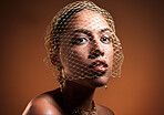 Stylish, elegant and portrait of a model with a net veil isolated on a brown background in studio. Fashion, vintage and face of a young retro model with a fashionable facial accessory on a backdrop