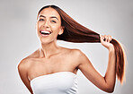 Happy, woman and portrait of healthy hair in studio for beauty, salon and hair care on grey background. Face, hair and pull by girl model smile for luxury, strong and shiny keratin results isolated