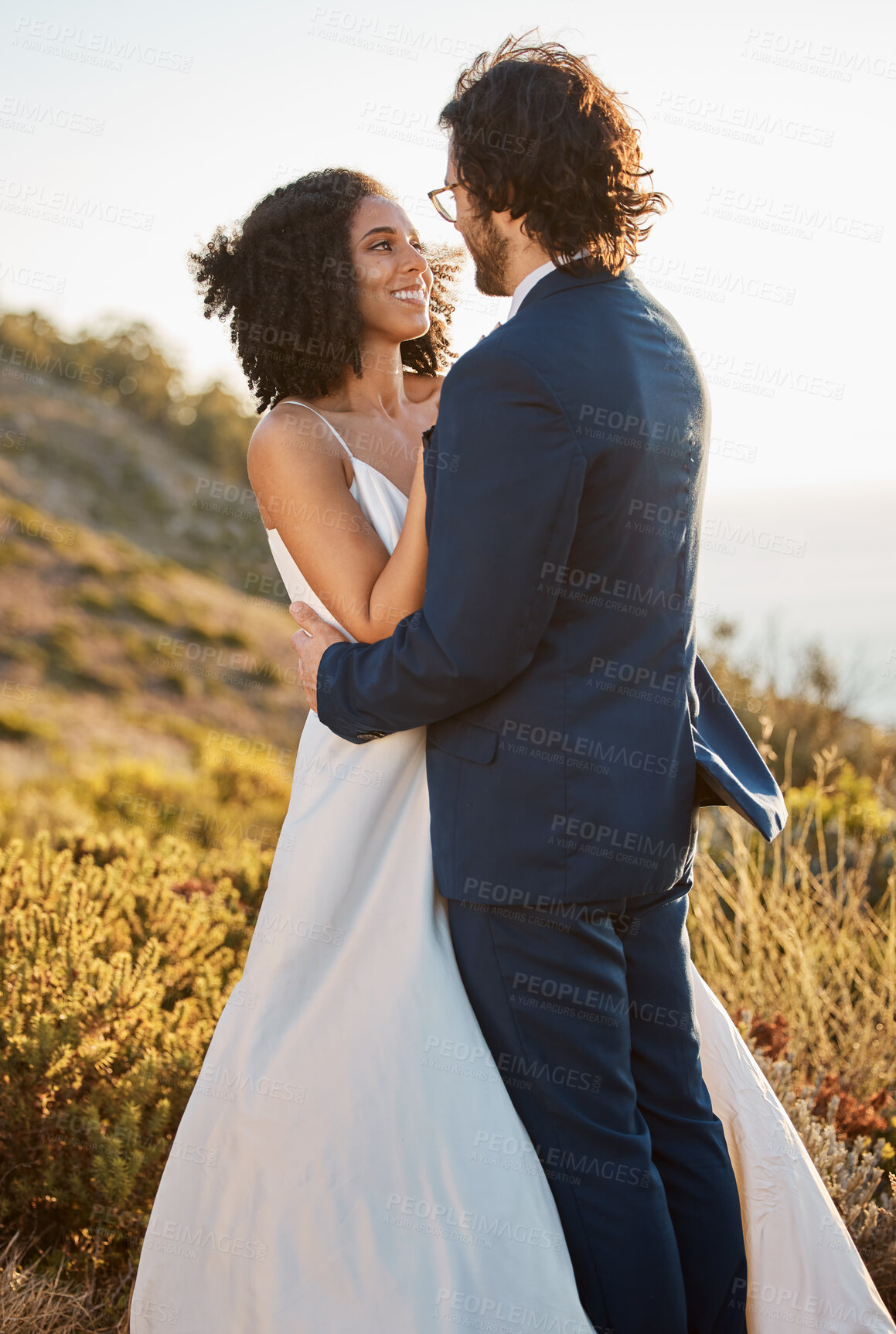 Buy stock photo Wedding couple, interracial and hug in nature, happy and excited while celebrating love, beginning and romance. Romantic, marriage and black woman bride with groom embrace, cheerful and smile 
