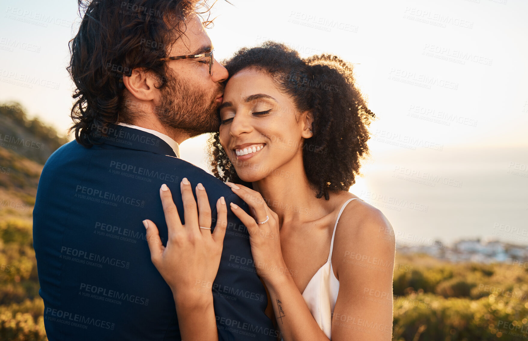 Buy stock photo Love, kiss and wedding with couple in nature for celebration, happiness and romance. Sunset, hug and affectionate with bride and groom in embrace at countryside for happy, marriage and smile together