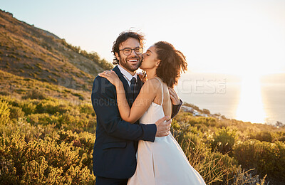 Buy stock photo Married couple, kiss and cheek and smile in nature for honeymoon, travel or sunset adventure together. Happy groom and bride kissing in love for marriage, relationship or commitment in the outdoors