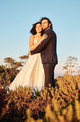 Buy stock photo Interracial couple, love and wedding at sunset, hug and happy for romance and relationship in nature. Marriage, bride and groom hug at outdoor ceremony and sweet on blue sky background space