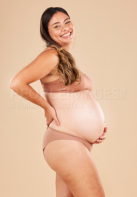 Buy stock photo Portrait, pregnant and stomach with a model woman in studio on a beige background for motherhood. Baby, beauty and wellness with an attractive young mother in underwear for pregnancy or body health