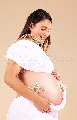 Buy stock photo Pregnant, mother and flowers on stomach, healthcare and excited for birth, smile and girl on brown studio background. Pregnancy, woman and mama with tummy, plants and nurture for wellness and growth