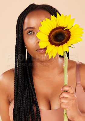Buy stock photo Portrait, beauty and sunflower with a black woman in studio on a beige background for natural treatment or body positivity. Spring, flower and skincare with a young female posing for wellness