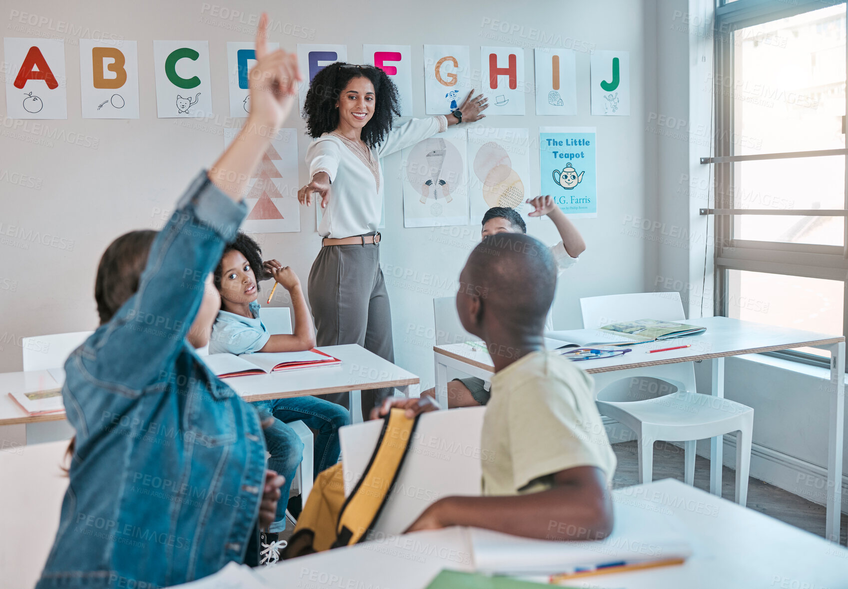 Buy stock photo Teacher, question and woman happy for education and teaching at school with kids learning the alphabet and answer quiz. Raised hands, learners and tutor helping a clever and smart classroom