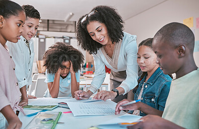 Buy stock photo Female teacher helping children with assignment, classroom in school and writing notes in book. Diversity in student group, educator reading kids notebook and learning together for assessment