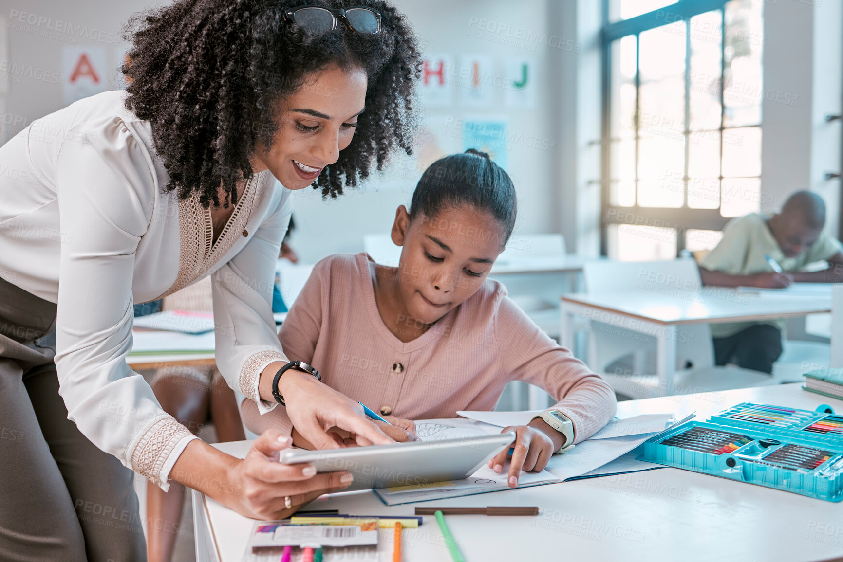 Buy stock photo Female teacher helping young girl, teaching creative work in book and children in sunny classroom. Education empowerment in school, educator speaking to student and learning mathematics at desk