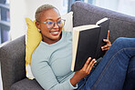 Black woman, relax smile and reading book on sofa in living room for calm peace, happiness and studying in home. Young african girl, happy student and relaxing with notebook or university textbook