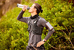 Man, runner fitness and drinking water outdoor for hike, cardio training or exercise workout. Athlete, sports break with bottle drink and sports wellness running in nature park or mountain hiking