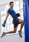 Gym, jump and kick of boxer man for sports workout, training and athlete practice with equipment. Energy, focus and strength of martial arts fighter at kickboxing fitness club with punching bag.