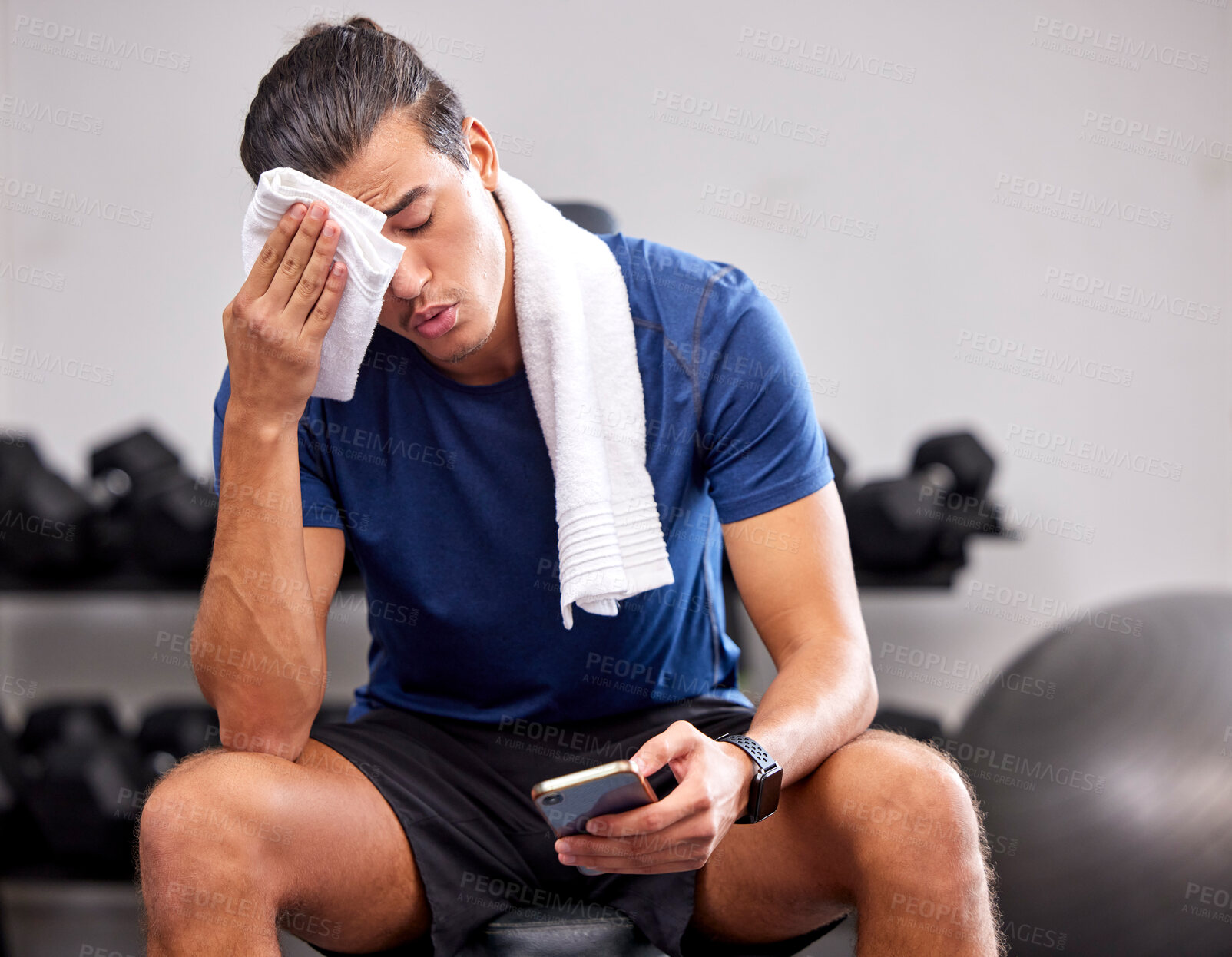 Buy stock photo Sweat, tired and man resting in the gym after a intense workout, exercise sports training. Fitness, sport and male athlete networking on social media with a phone after exercising in wellness studio.