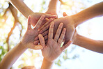 Hands, community and group in unity for trust, support or teamwork goals piling together below for collaboration in nature. Hand of people in solidarity, union or coordination for united team effort