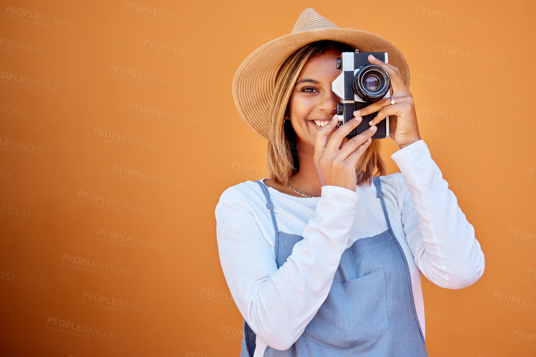 Buy stock photo Photographer, portrait and woman shooting a picture or photo with a retro camera isolated in an orange background. Happy, studio and female taking creative shots or fashion photographs as photography