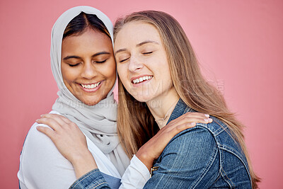 Buy stock photo Hug, happy and women friends in a studio with love, care and bond for friendship or support. Happiness, smile and muslim woman embracing a lady from Australia while isolated by a pink background.