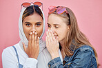 Woman, friends and secret whisper of gossip in shock against a pink studio background. Women sharing secrets, rumor or surprise whispering in the ears for hidden story, sale or discount announcement