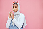 Young Islamic girl, smell flower and modern gen z or millennial fashion, zen freedom and calm peace in pink background. Muslim female, flowers scent and hijab with trendy or edgy clothes in studio