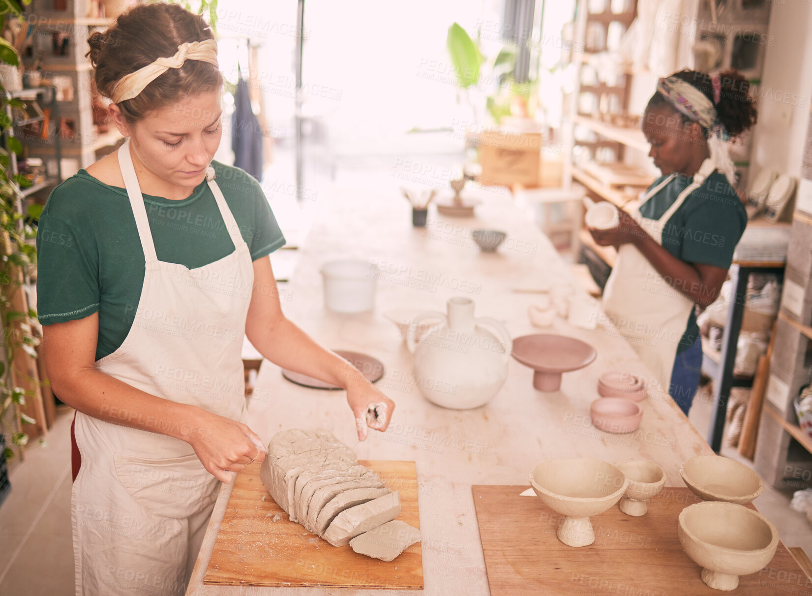 Buy stock photo Pottery workshop and woman dividing clay for sculpting process and productivity at creative business. Focus, concentration and skill of interracial artist team working in professional workspace.