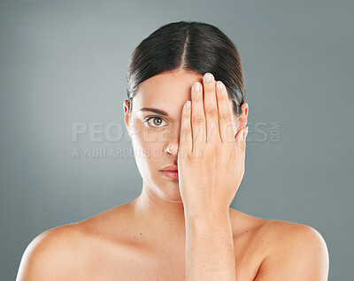 Face, cover and portrait of a woman with a hand on eye isolated on a grey studio background. Skincare, beauty and serious model hiding eyes for dermatology, botox problem and cosmetics on a backdrop
