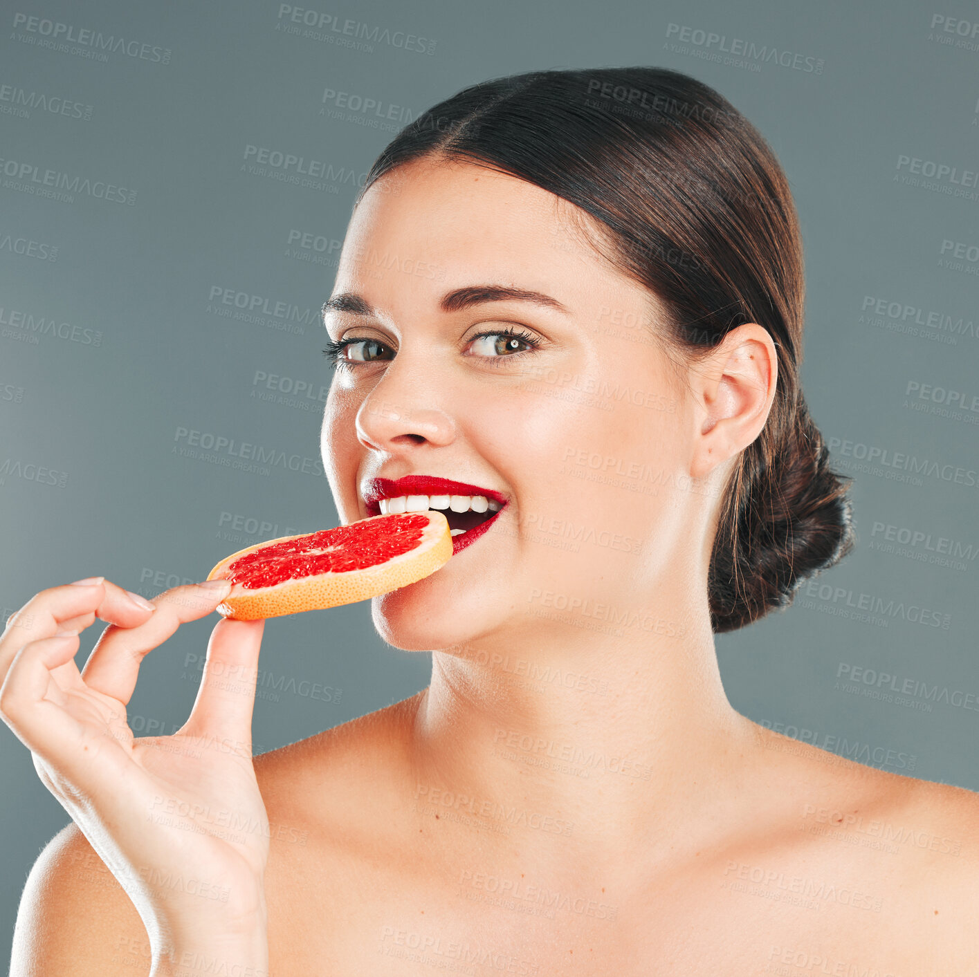 Buy stock photo Fruit bite, portrait and woman eating a grapefruit for nature and wellness aesthetic in a studio. Model, beauty and natural skincare of a young person with red lipstick hungry for vitamin c nutrition