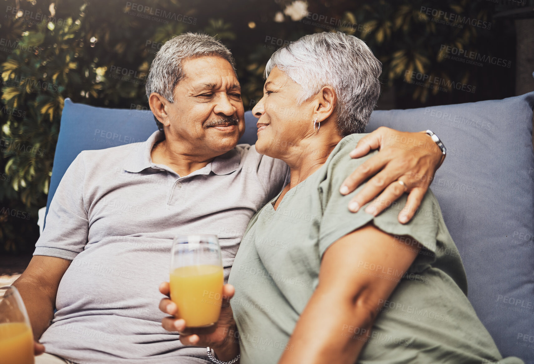 Buy stock photo Senior couple, hug and juice on a garden patio sofa with love and care for marriage and retirement. Conversation, morning talking and relax discussion of elderly man and woman outdoor with happiness