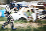 Paintball, aim and man with a gun for a game with blur motion at an outdoor arena or field. Challenge, competition and male soldier with a camouflage military outfit shooting a rifle on a battlefield